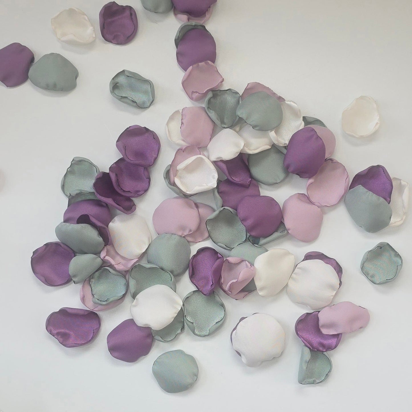 A mix of different shades of purple and sage green rose petals in Ivory flower girl basket. Includes Wisteria, Dusk Purple, Ivory and dusty sage rose petals for flower girl toss, aisle decor, photo flatlays, table scatter. Perfect for future brides planning a classic wedding or Love in Bloom or Whimsical bridal shower event ideas.