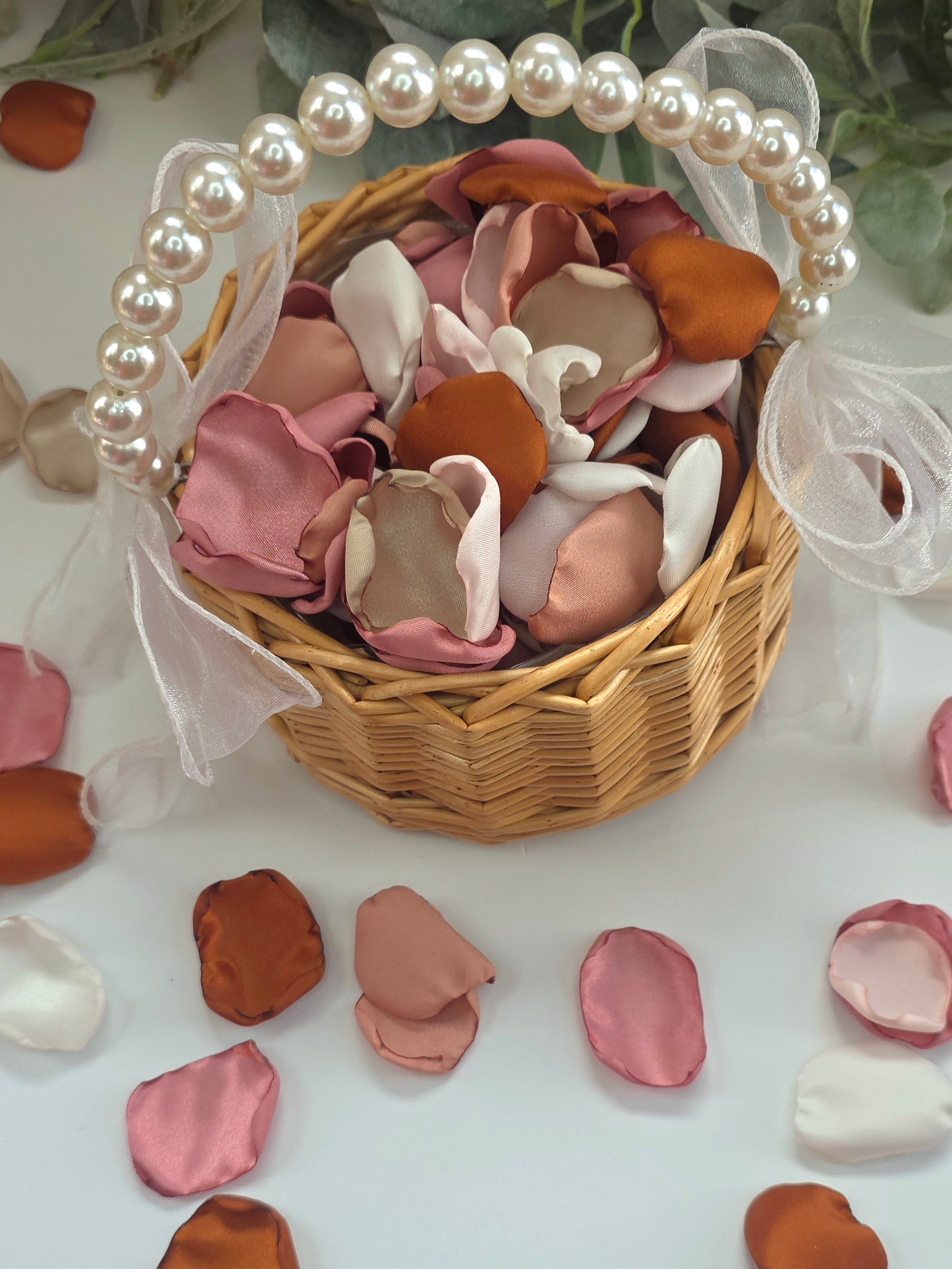 Auburn, burnt orange, beige, blush pink rose petals in a rustic basket  for flower girl tossing, aisle decor, flatlays, backdrop accents or tablescape table scatter, decor ideas. A fall color palette for the future bride planning a western, rustic wedding ceremony or natural, nuetral colored bridal shower event