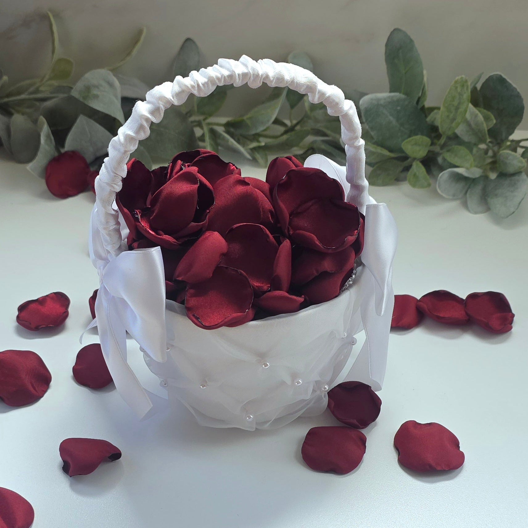 Burgundy rose petals in white flower girl basket for tossing, aisle decor, classic fall wedding decor. Ideas for future brides planning an elegant wedding ceremony or bridal shower event.