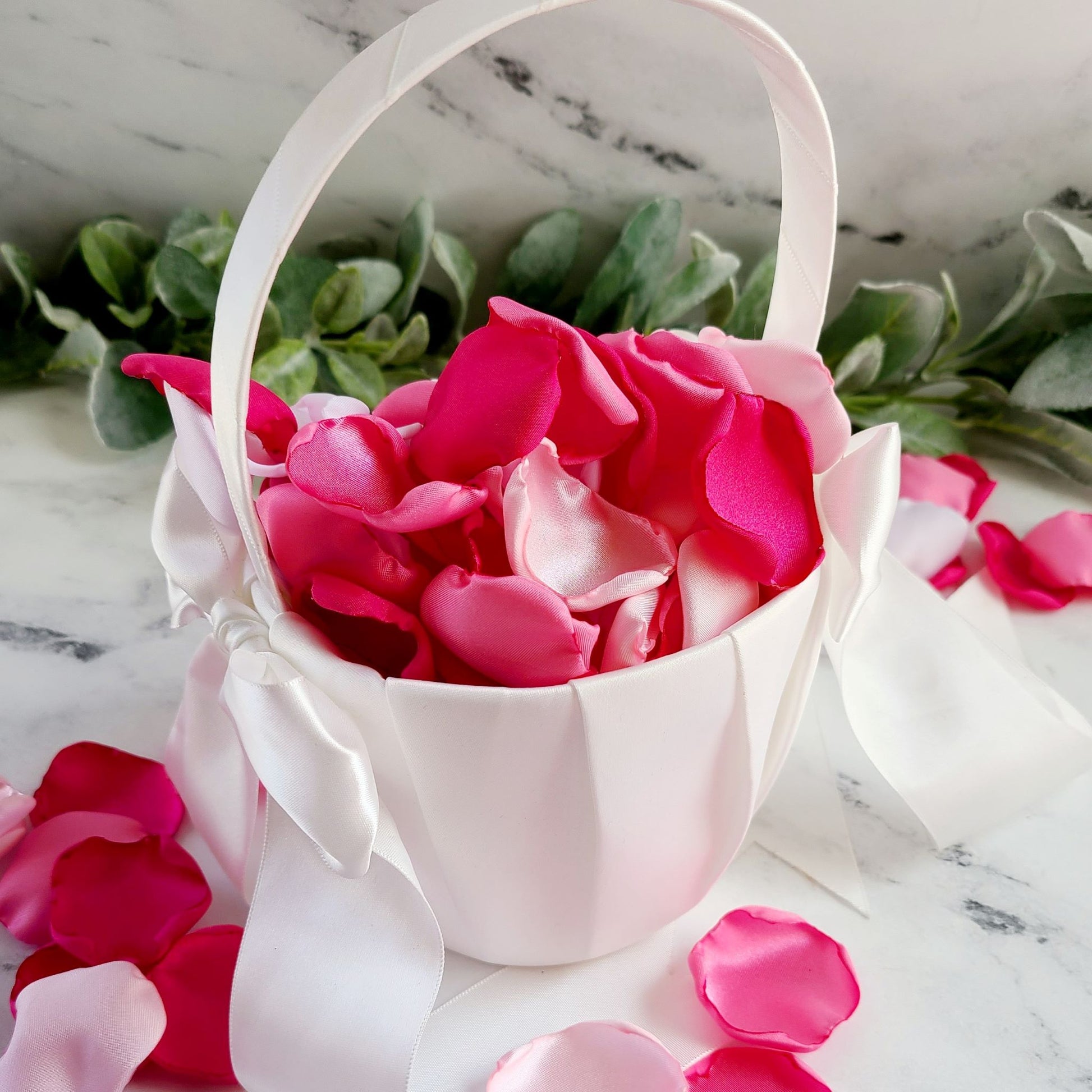 Pink and white rose petals in white flower girl basket