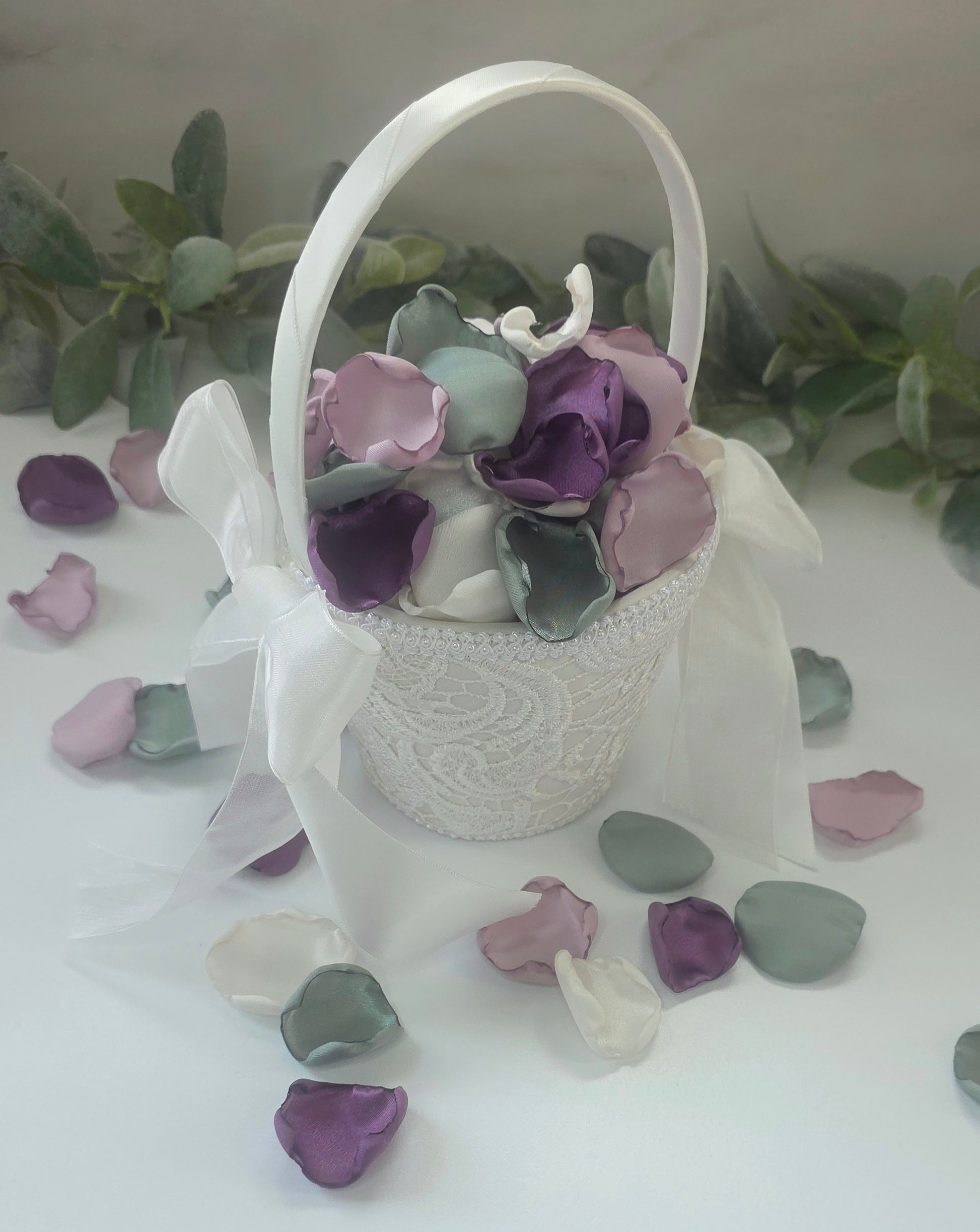 A mix of different shades of purple and sage green rose petals in Ivory flower girl basket. Includes Wisteria, Dusk Purple, Ivory and dusty sage rose petals for flower girl toss, aisle decor, photo flatlays, table scatter. Perfect for future brides planning a classic wedding or Love in Bloom or Whimsical bridal shower event ideas.
