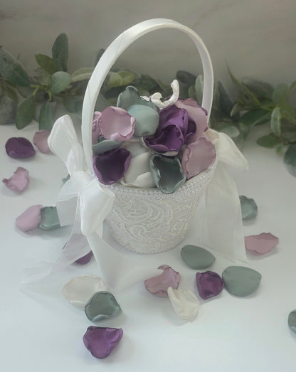 A mix of different shades of purple and sage green rose petals in Ivory flower girl basket. Includes Wisteria, Dusk Purple, Ivory and dusty sage rose petals for flower girl toss, aisle decor, photo flatlays, table scatter. Perfect for future brides planning a classic wedding or Love in Bloom or Whimsical bridal shower event ideas.